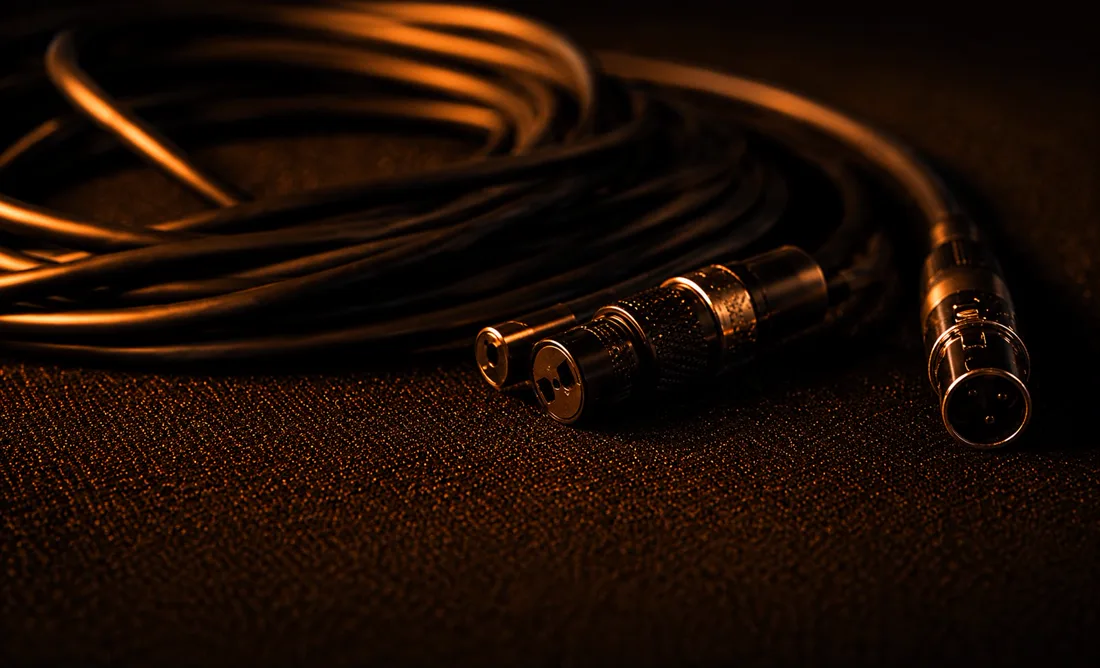 Cables XLR enrollados y conectores iluminados en naranja cálido